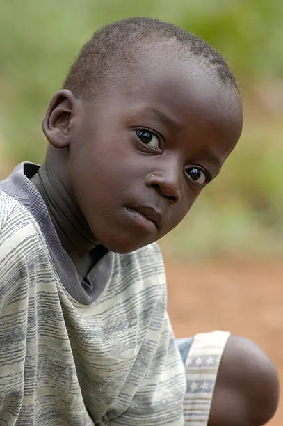 a-child-in-a-gray-checked-shirt-sitting-outdoors-and-looking-toward-the-camera