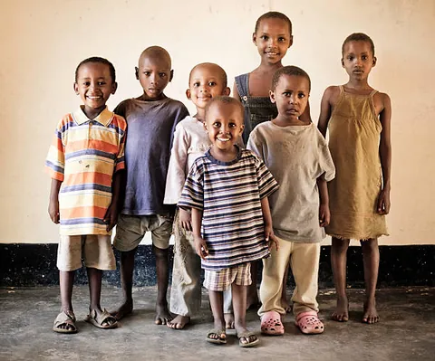 a-group-of-children-standing-together-against-a-light-colored-wall