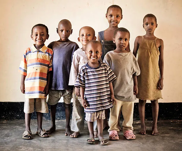 A group of children standing together against a light-colored wall. a-group-of-children-standing-together-against-a-light-colored-wall-for-owaid-orphan-and-widow-support