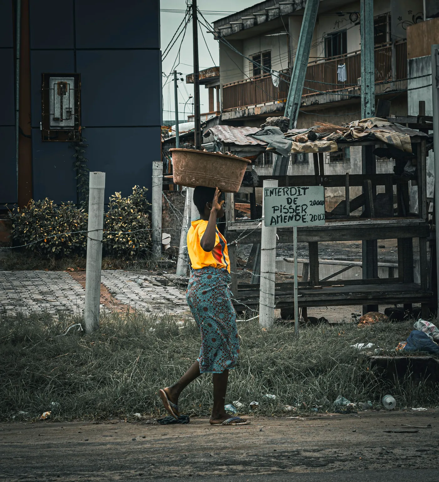 A person walking along a narrow street lined with multistory buildings. a-person-walking-along-a-narrow-street-lined-with-multistory-buildings-for-owaid-orphan-and-widow-support