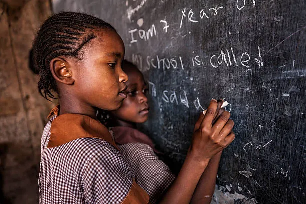 A student writing with chalk on a classroom blackboard. a-student-writing-with-chalk-on-a-classroom-blackboard-for-owaid-orphan-and-widow-support