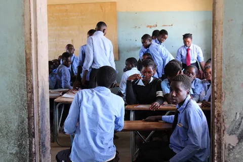 students-in-blue-uniforms-gathering-around-desks-in-a-classroom
