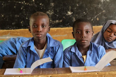 students-in-blue-uniforms-reading-from-open-books-at-a-classroom-desk