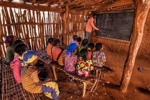 children-seated-on-wooden-benches-facing-a-chalkboard-in-a-timber-classroom