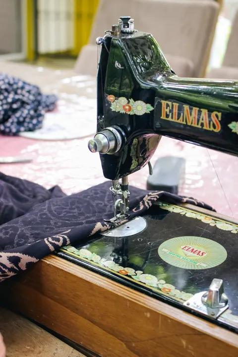 a-sewing-machine-and-patterned-fabric-on-a-wooden-worktable