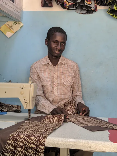 a-tailor-seated-behind-patterned-fabric-at-a-sewing-worktable