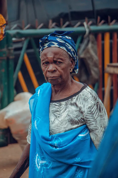an-older-woman-wearing-a-blue-wrap-and-a-patterned-headscarf