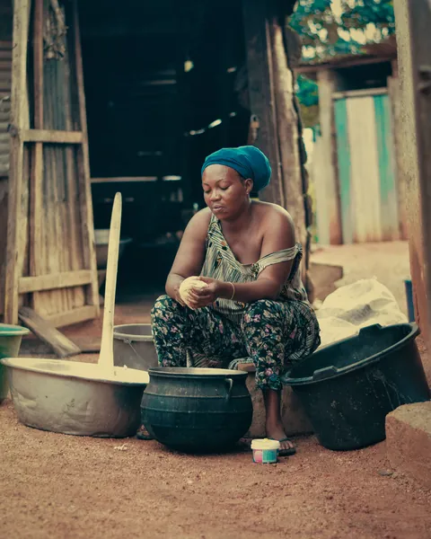 a-woman-sitting-beside-basins-outside-a-wooden-doorway
