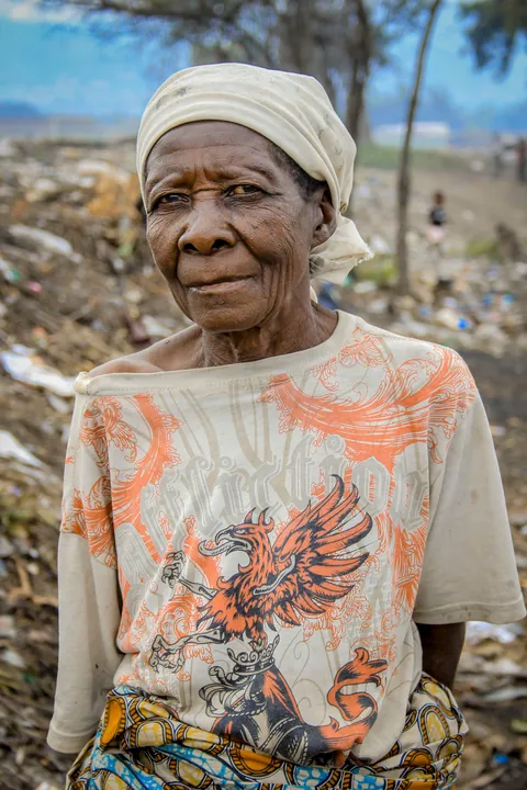 an-older-woman-wearing-a-light-headscarf-and-a-patterned-top-outdoors