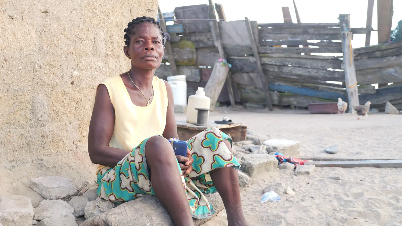 a-woman-in-a-yellow-top-sitting-beside-a-wall-in-a-home-courtyard-for-owaid-orphan-and-widow-support