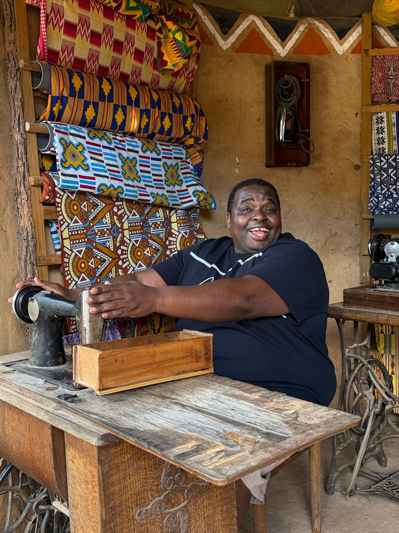 a-woman-seated-at-a-sewing-machine-in-a-shop-filled-with-colorful-fabric-for-owaid-orphan-and-widow-support